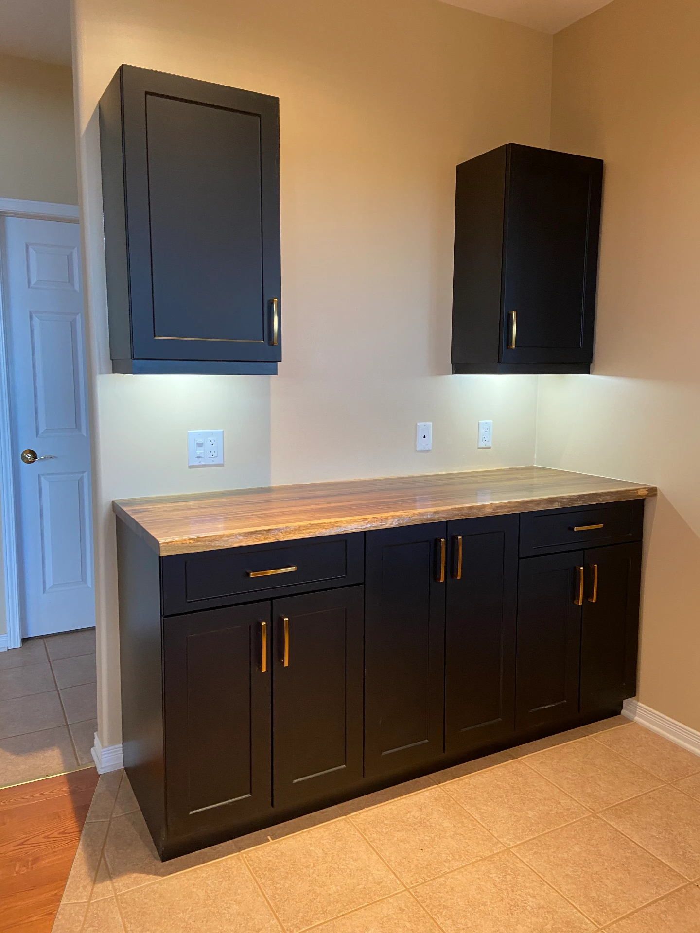 Custom dark butler pantry with live-edge wood countertop and brass pulls